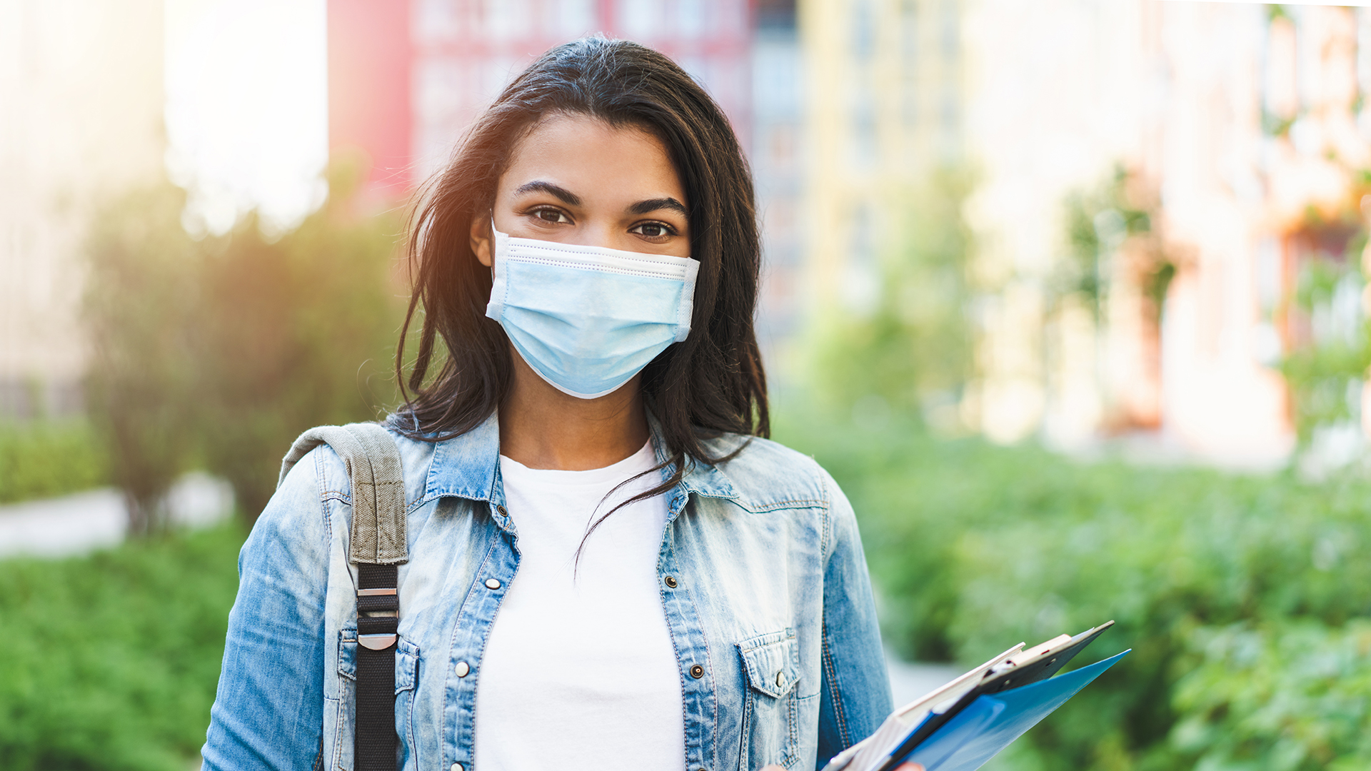 Female student walking to class wearing a surgical mask